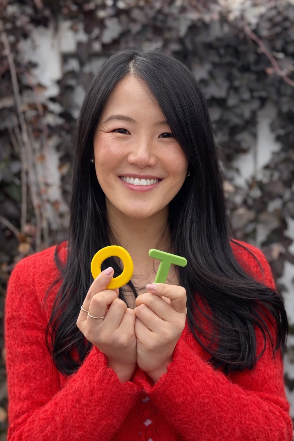 Dr. Jenny Li smiling and holding toy letters O and T